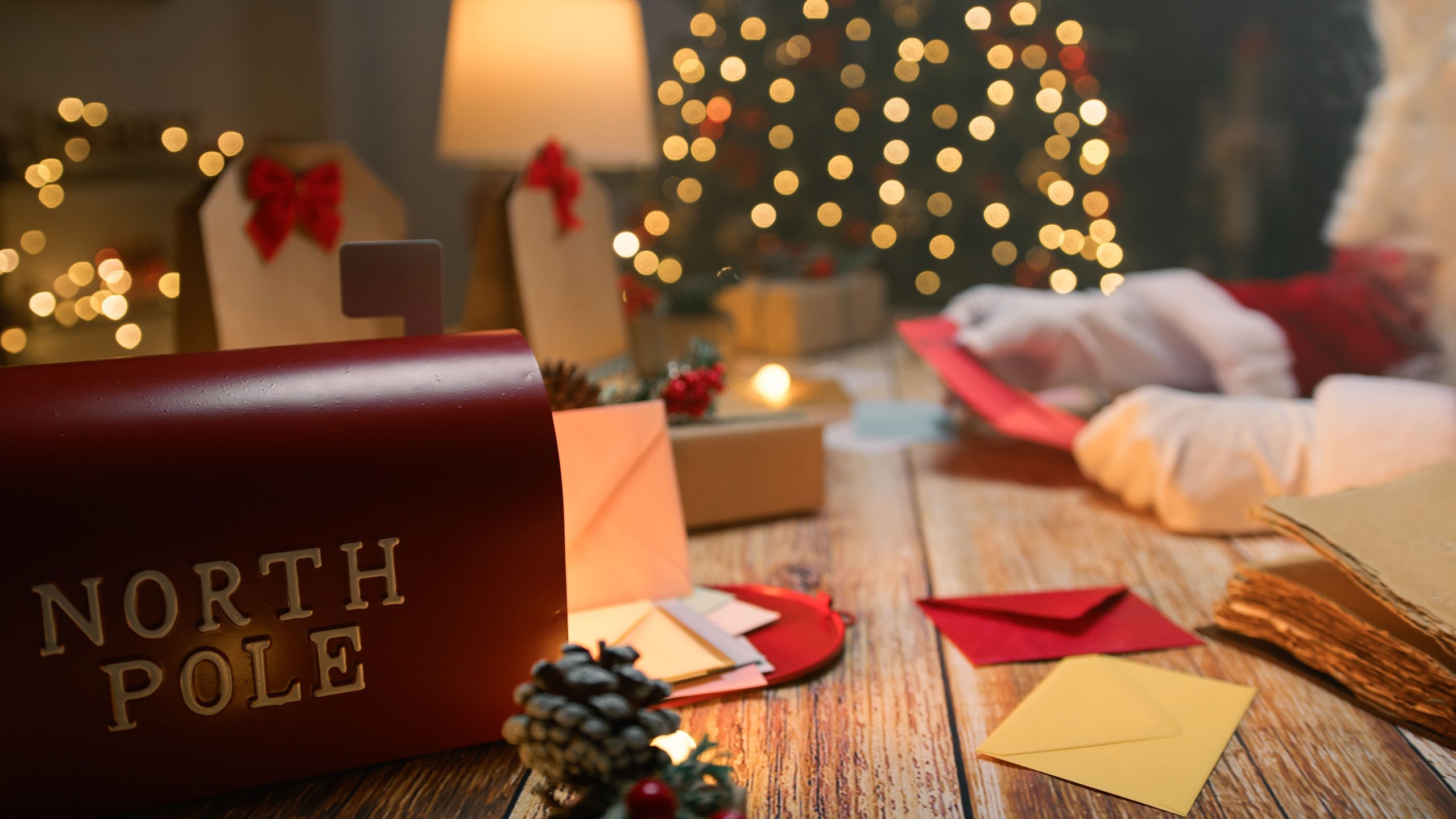 Santa writing a personalized Dear Santa letter surrounded by gifts and a warm mug