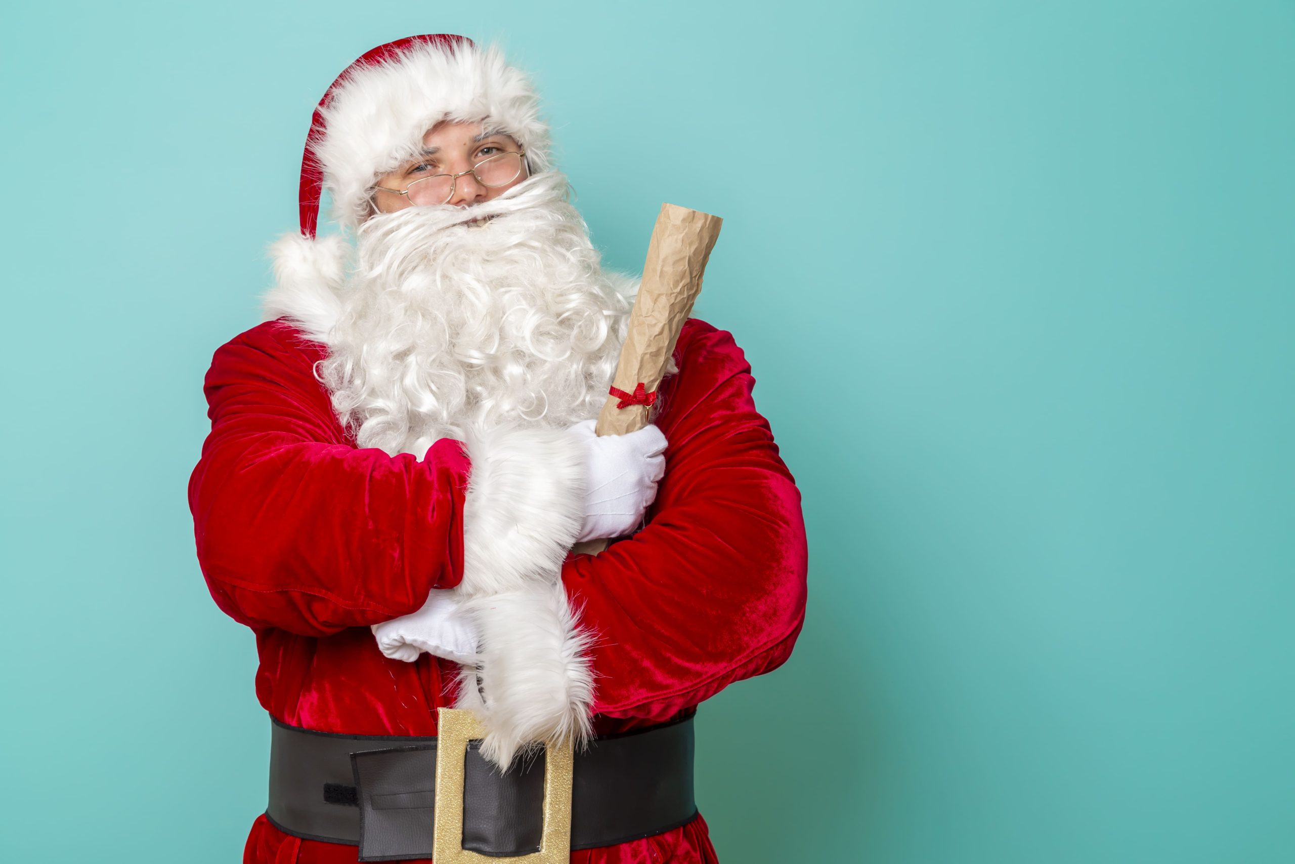 Santa Claus holding a rolled parchment letter tied with a ribbon
